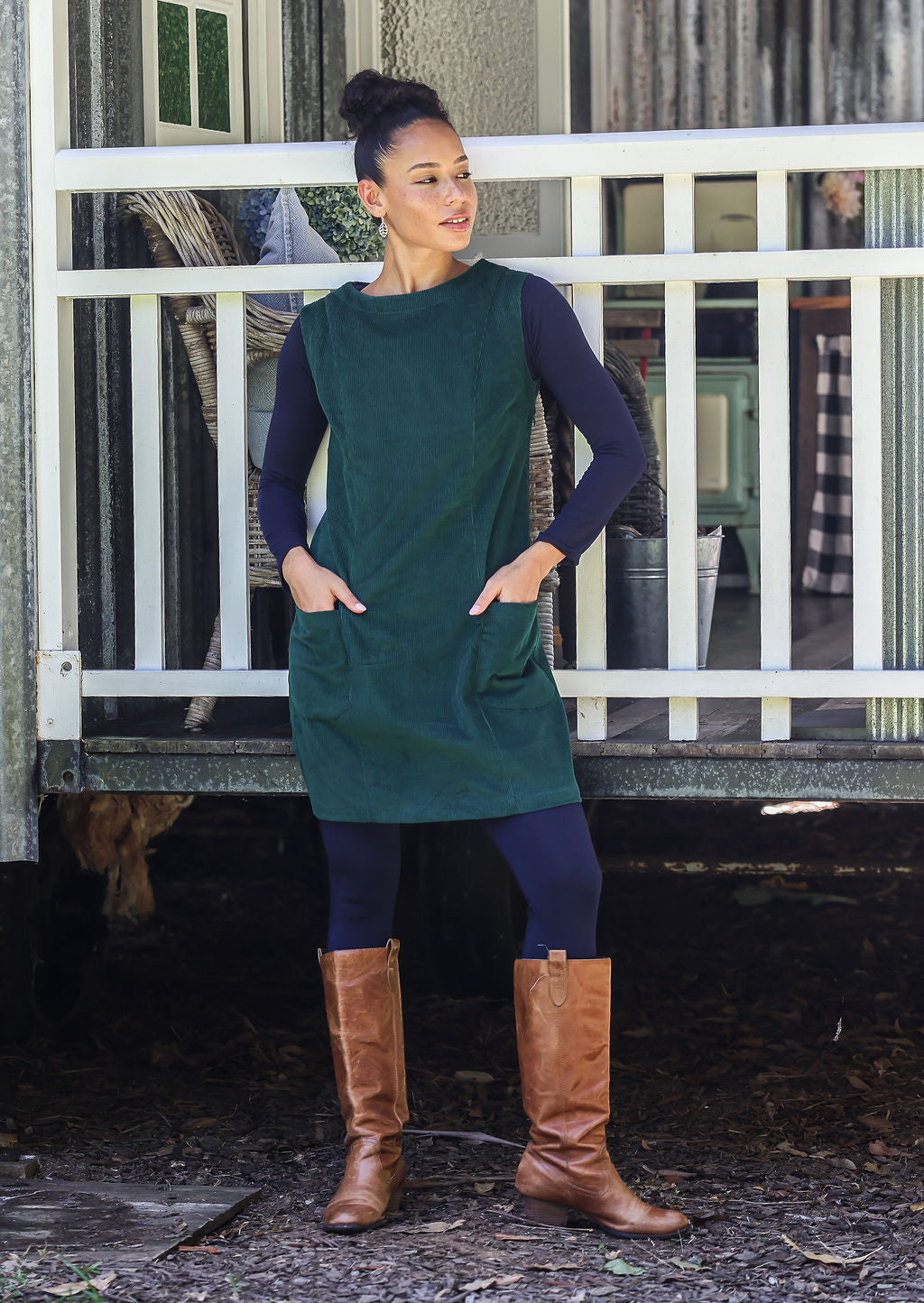 Woman wearing cotton corduroy tunic in dark green with boat neck and front pockets