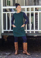 Woman wearing cotton corduroy tunic in dark green with boat neck and front pockets