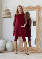 Woman wearing cotton corduroy tunic in cabernet with boat neck with one hand in pocket