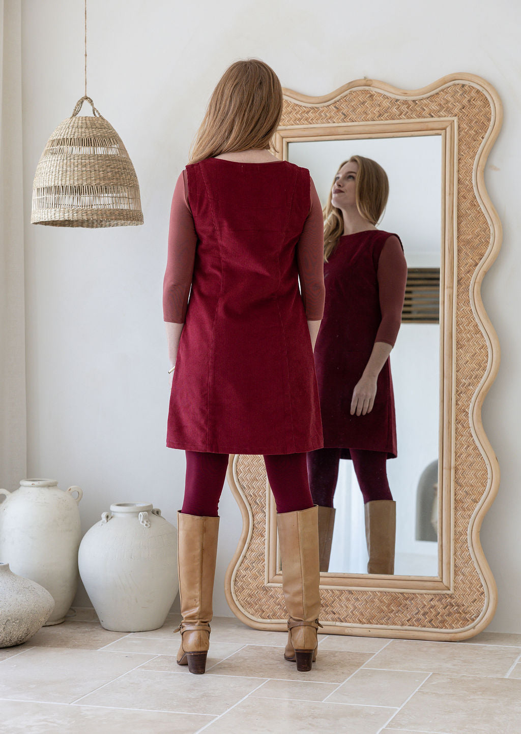 Woman standing backwards wearing cotton corduroy tunic in cabernet 