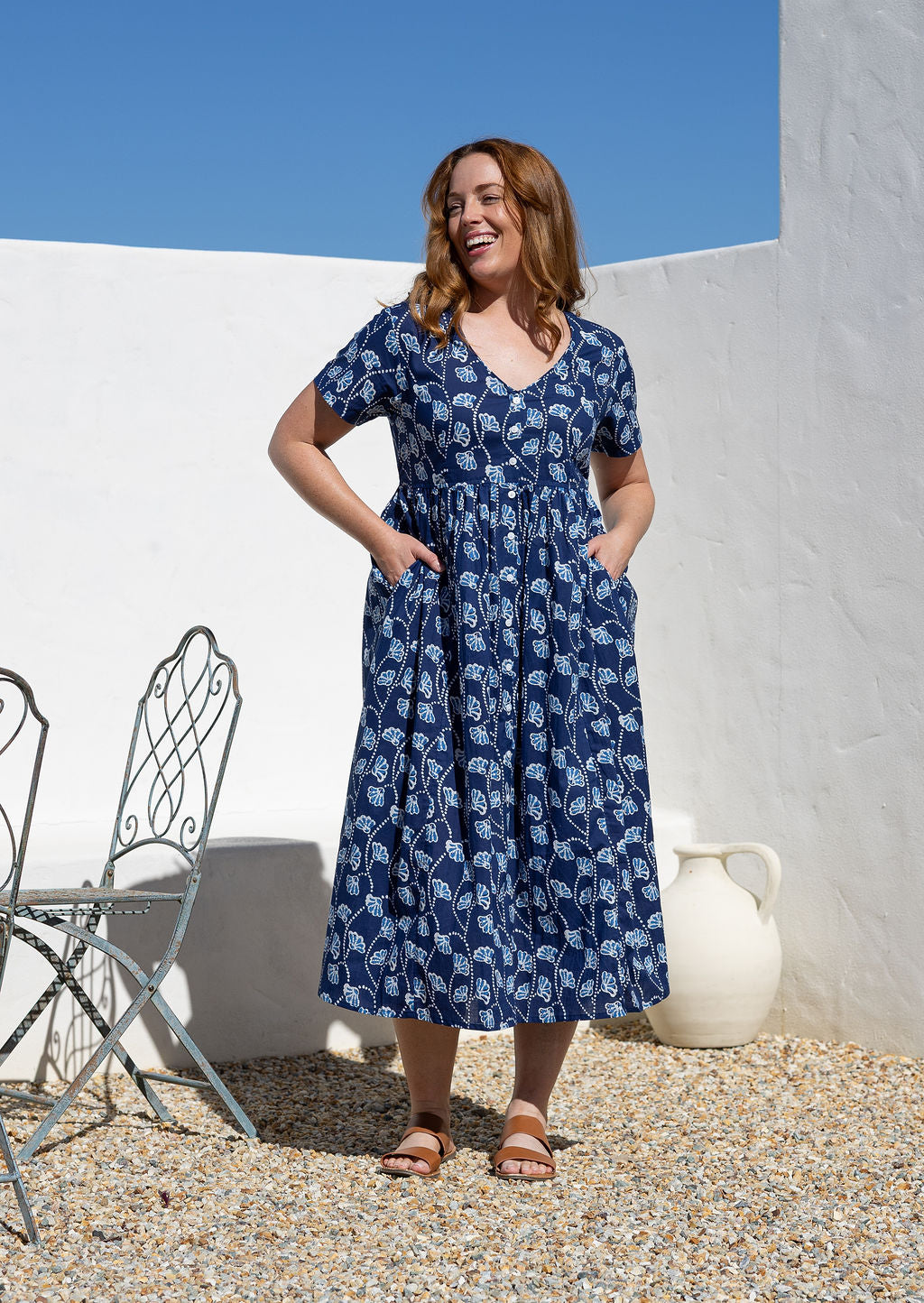 Woman posing in a relaxed fit, short sleeved, floral cotton dress with V- neckline, drawstring waist tie and pockets 