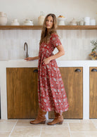 Woman stands sideways wearing a 100% cotton dress with short sleeves, pockets, and a drawstring tie at the back.