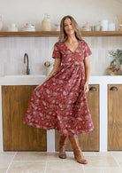 Woman in a red floral dress standing in a kitchen.