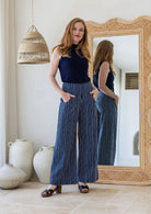 Model wearing a wide leg 100% cotton pant with navy based white striped print standing against a mirror