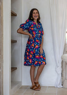 Woman standing wearing a 100% cotton dress with royal blue based floral print