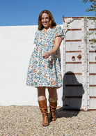 Woman wearing a knee length relaxed fit button through 100% cotton dress with elbow length sleeves