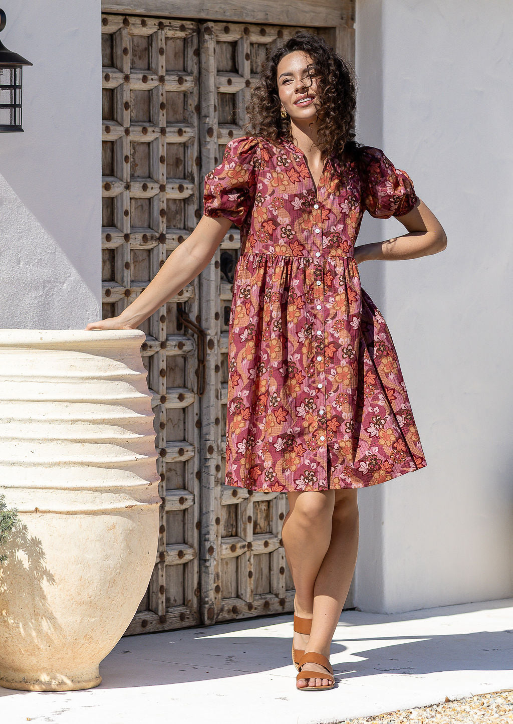 Woman wearing a warm toned Japanese style print dress with, relaxed fit, empire waistline and elasticated elbow length sleeves