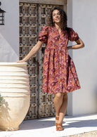 Woman wearing a warm toned Japanese style print dress with, relaxed fit, empire waistline and elasticated elbow length sleeves