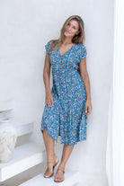 Woman standing in midi length rayon dress button through dress with V-neckline and elasticated waistband