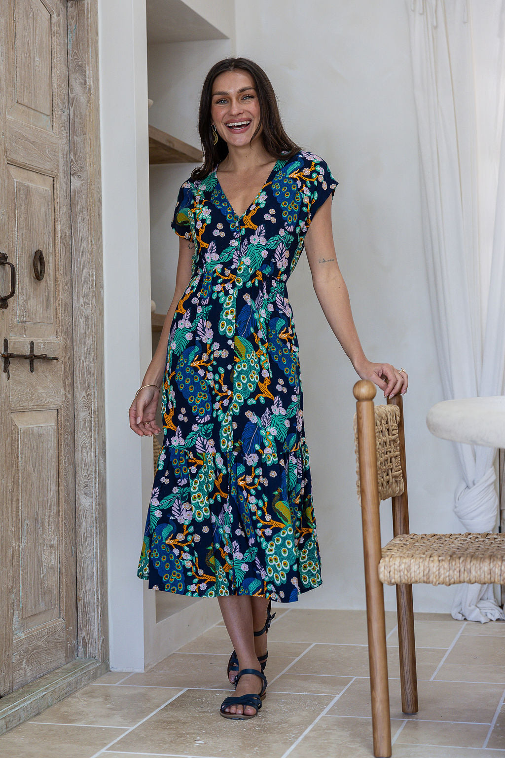 Woman standing in midi length rayon dress button through dress with V-neckline and elasticated waistband