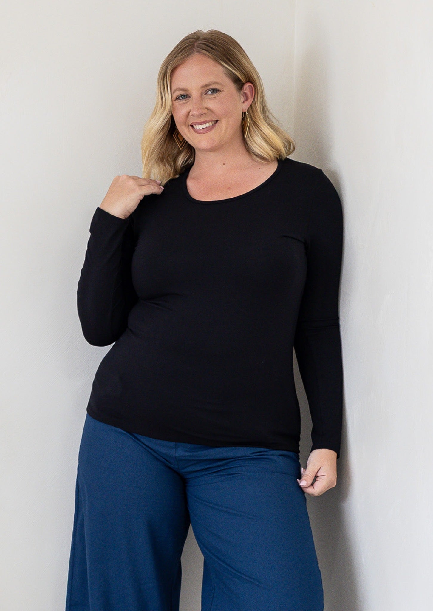 A woman modelling a black long-sleeve stretch rayon round neck top and blue pants