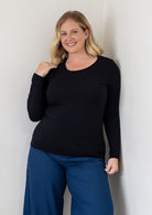 A woman modelling a black long-sleeve stretch rayon round neck top and blue pants