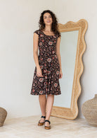 Model in knee length, black 100 percent cotton scoop neck Indian traditional style print dress with pockets and cap sleeves 