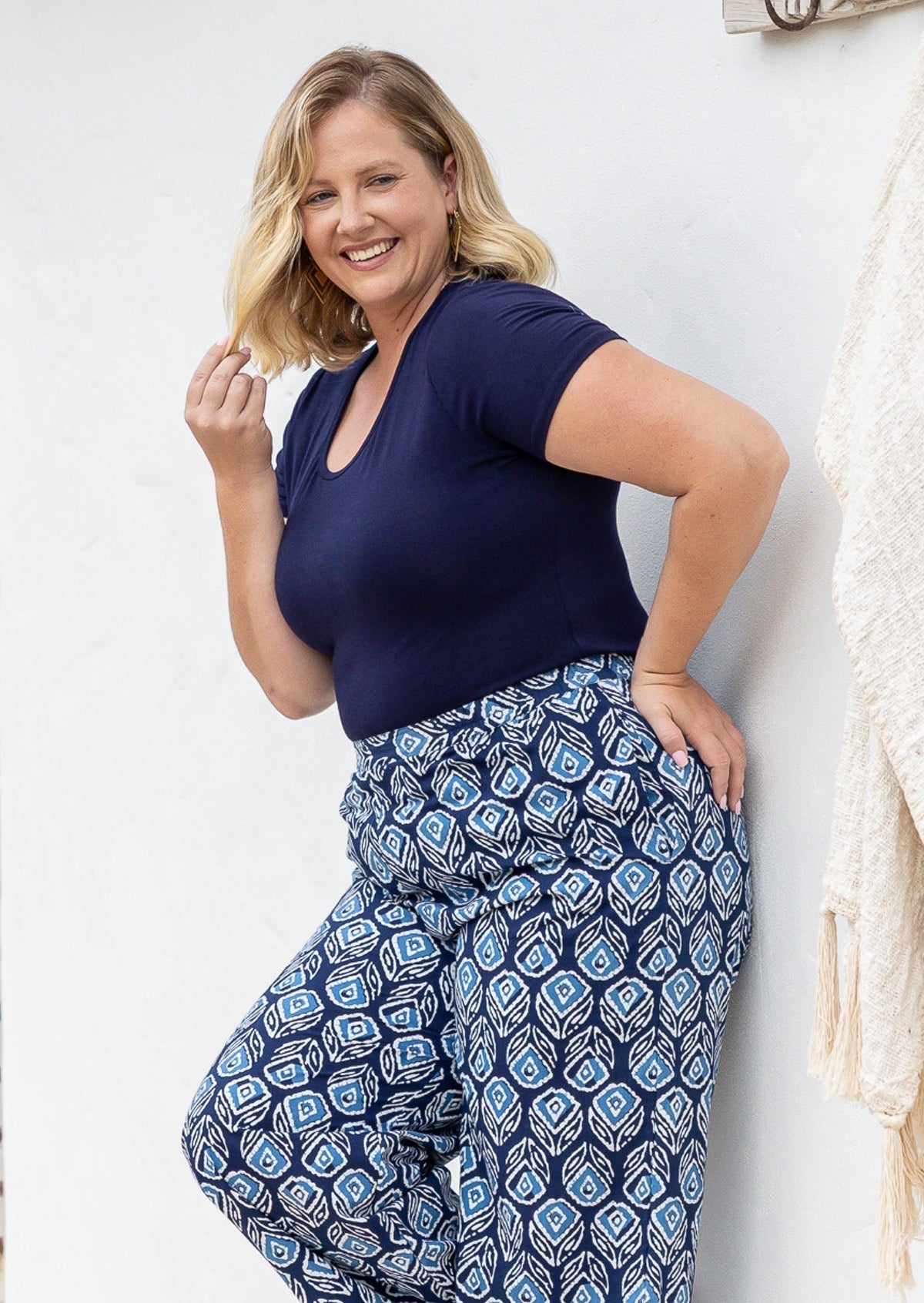 Woman wearing a scoop neck navy blue rayon fitted t-shirt standing against a white wall