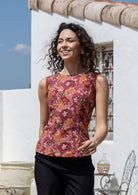 Woman standing in a floral sleeveless cotton top with plain trim around the arms.