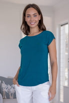 Woman wearing a teal soft stretch rayon jersey t-shirt, with a hand in pants pocket