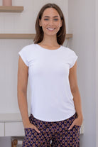 Woman wearing a white soft stretch rayon jersey t-shirt, with hands in pockets of floral pants