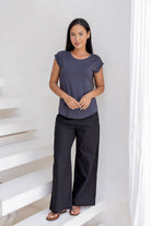 Woman wearing a 100% rayon dark grey shell top and black pants standing on a white staircase.