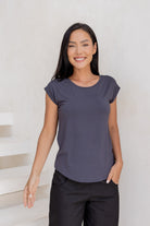 Woman wearing a 100% rayon dark grey shell t-shirt and black pants against a light background