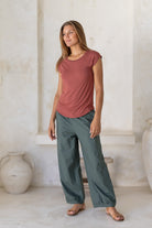 Woman wearing a 100% rayon terracotta shell t-shirt standing against a white wall.