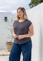 Woman poses in a dark grey v-neck short cap sleeve rayon top