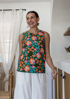 Woman wearing a sleeveless 100% cotton top with round neckline in olive green based floral print 