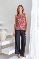 Woman standing in front of white wall wears 100% cotton sleeveless floral print top with keyhole button closure at the back