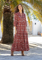 Woman wearing a 100% cotton tiered maxi dress in red based floral print