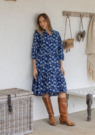 Woman poses in cotton tiered over the knee dress with 3/4 sleeves, buttoned bodice and V-neckline