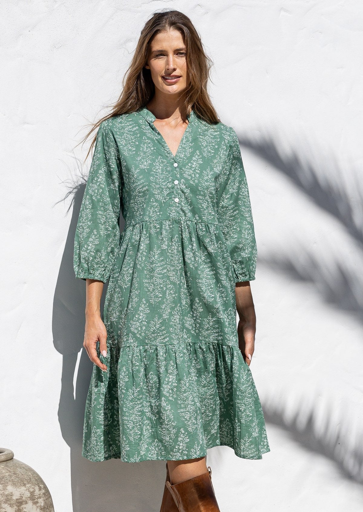 Woman poses in cotton tiered over the knee dress with 3/4 sleeves, buttoned bodice and V-neckline