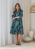 Woman wearing a 100% cotton tiered over the knee dress with 3/4 sleeves, buttoned bodice and V-neckline