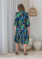 Model stands backwards on in cotton over the knee length relaxed fit dress with 3/4 sleeves, paired with sandals 