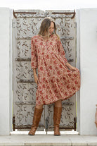 Woman flaunting cotton tiered dress in cream based floral print, with 3/4 sleeves, buttoned bodice and V-necklin
