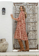Model stands side on in cotton over the knee length relaxed fit dress with 3/4 sleeves, paired with brown boots 