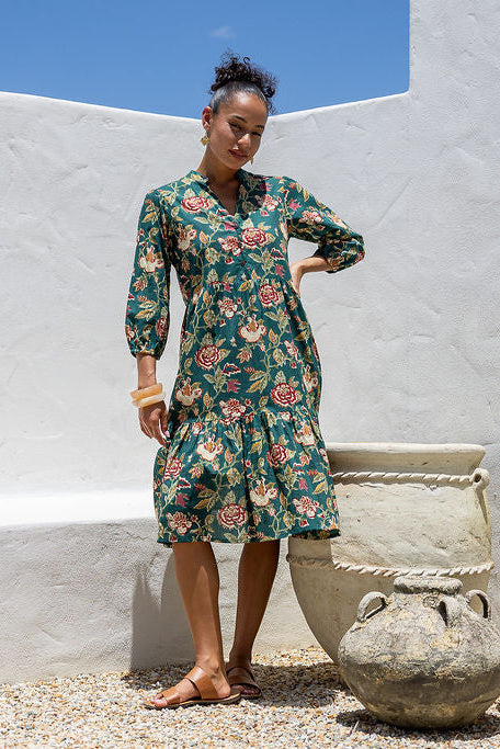 Woman wearing a 100% cotton tiered over the knee dress with 3/4 sleeves, buttoned bodice and V-neckline