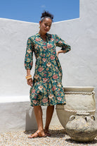 Woman wearing a 100% cotton tiered over the knee dress with 3/4 sleeves, buttoned bodice and V-neckline