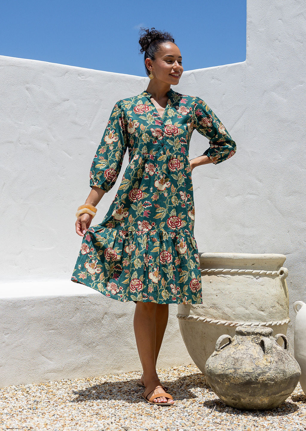Woman flaunting cotton tiered dress in green  floral print, with 3/4 sleeves, buttoned bodice and V-neckline