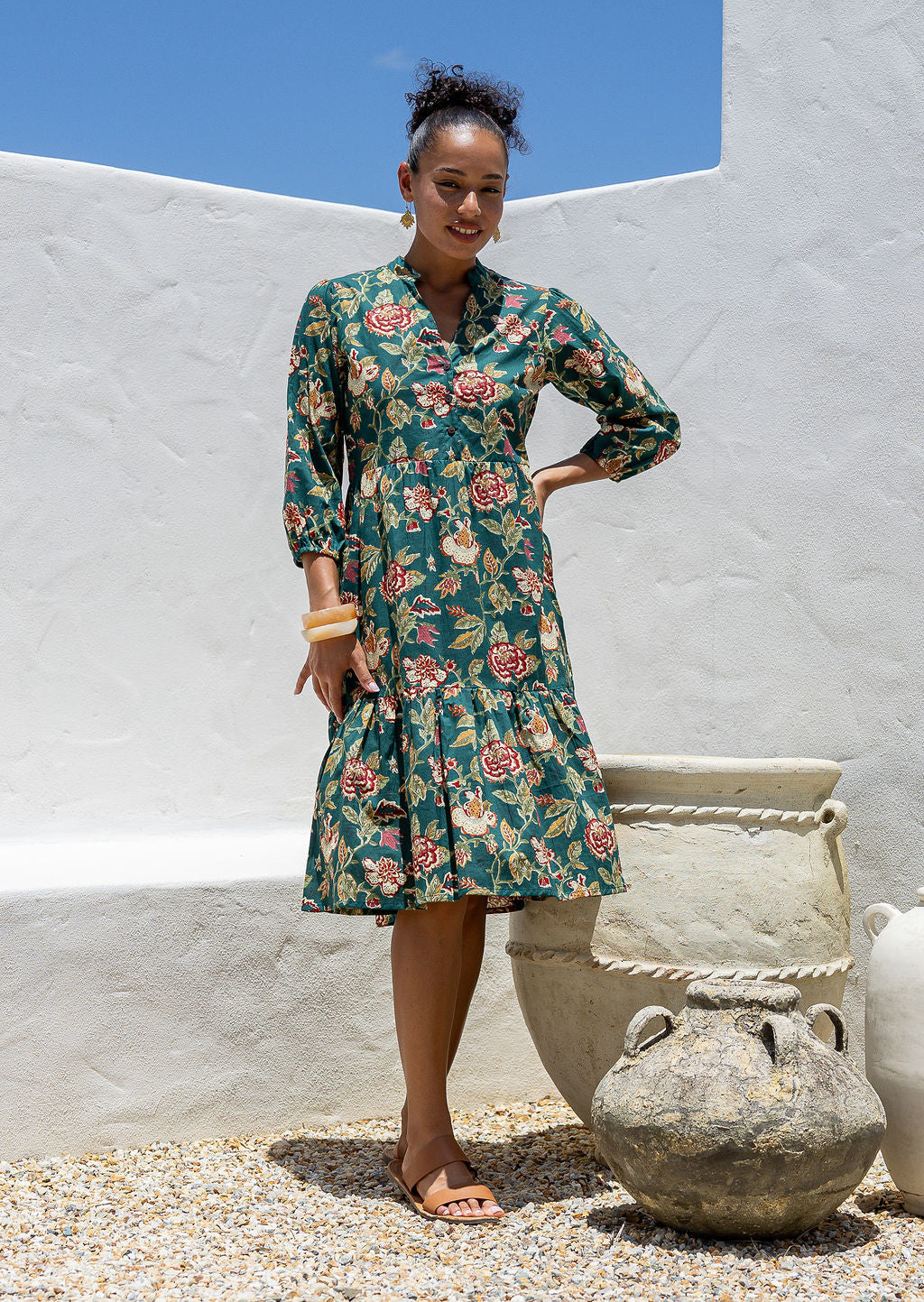 Woman poses in cotton tiered over the knee dress with 3/4 sleeves, buttoned bodice and V-neckline