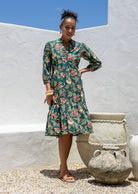 Woman poses in cotton tiered over the knee dress with 3/4 sleeves, buttoned bodice and V-neckline