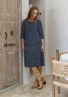 Woman wearing a relaxed fit below knee length cotton dress with 3/4 sleeves, pockets and round neckline.
