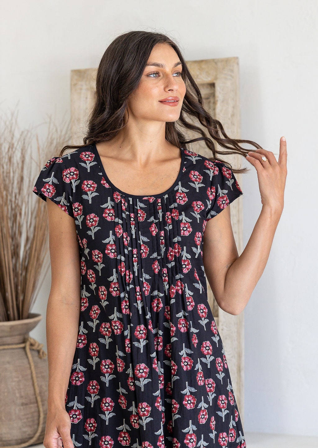 Close up of a woman poses in a 100% cotton navy black based floral dress with round neckline and cap sleeves