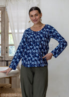 Model wearing a flattering long sleeve top with navy blue based florals with plain pants.