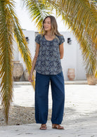 Woman wearing 100 percent cotton top with short cap sleeves and longer back hem.