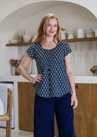Woman wearing a blue floral top and plain pants in a kitchen setting
