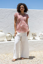 Woman wearing a rose pink based floral print short sleeve top with scoop round neckline and pleated detail across the bodice