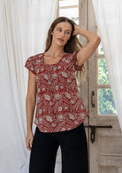 Woman wearing 100 percent cotton top with short cap sleeves and longer back hem.