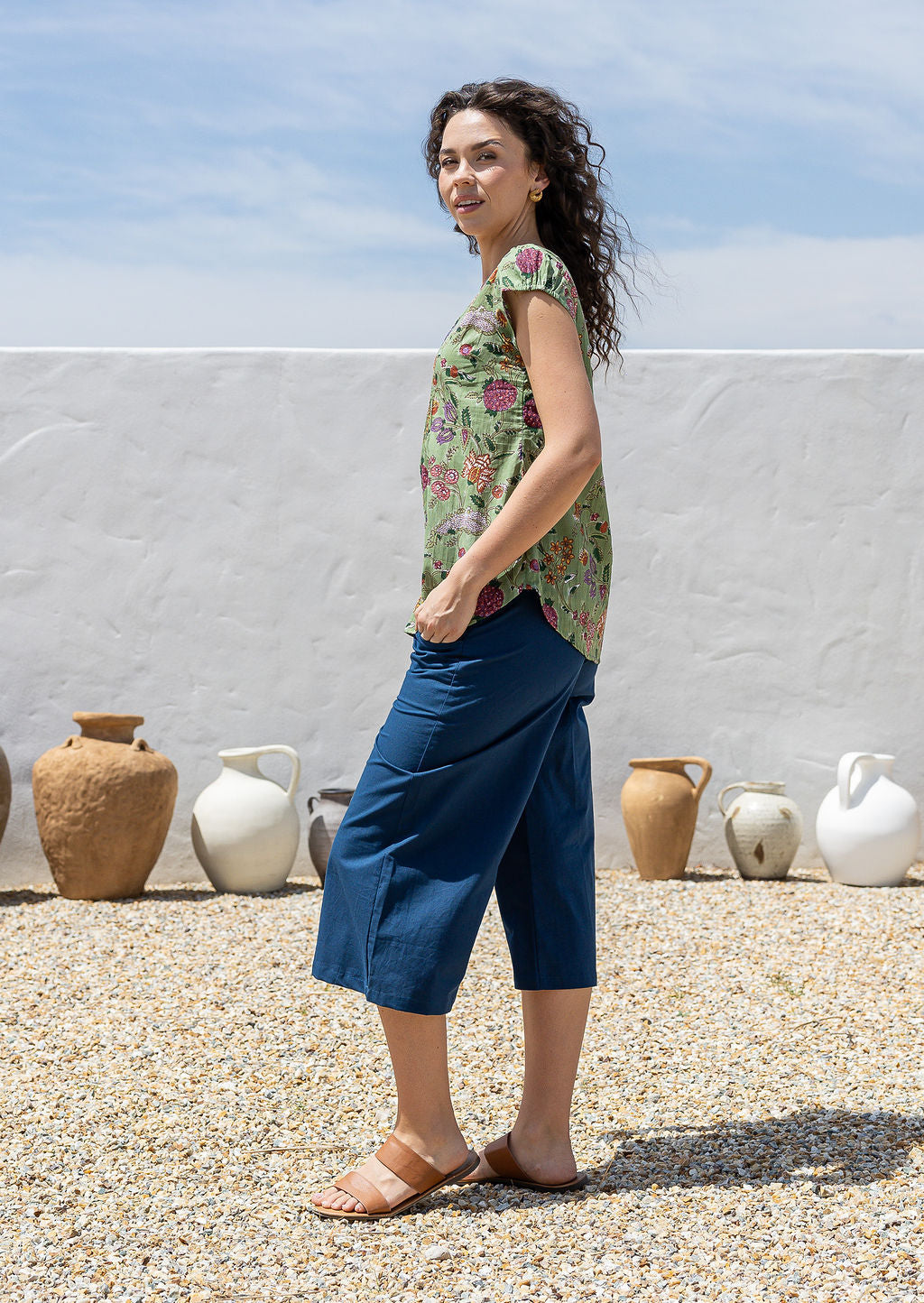 Woman wearing a moss green based multi-coloured folk art style florals 100% cotton top 