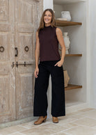 Woman wearing a sleeveless brown stretch rayon jersey top with a mock turtleneck, paired with black pants and tan boots