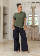 Woman wearing an olive green short-sleeve twist-front rayon T-shirt paired with black cotton pants