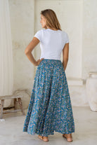Woman posing in pull on style printed rayon pants in blue based floral print with elastic waist.